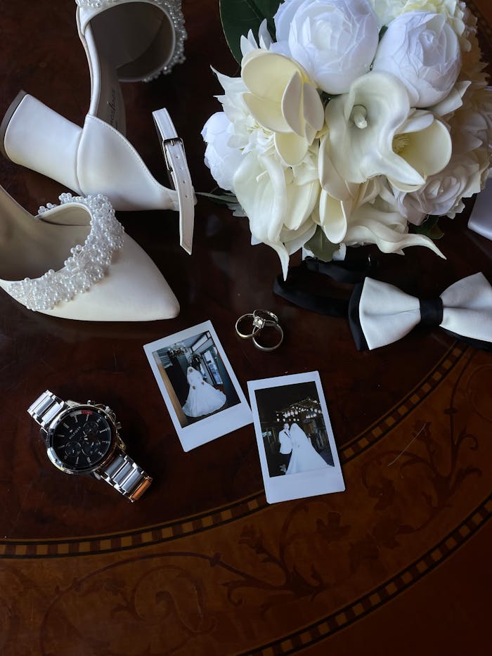 Elegant arrangement of wedding items including shoes, bouquet, and photos on a table.